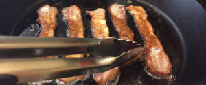 Tongs lifting bacon